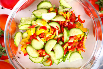 Top view of fresh vegetable salad with cucumber and sweet peppers on transparent plate. Healthy homemade food concept