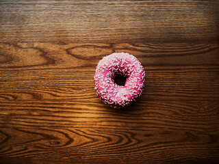 Pink donut with colorful sprinkles isolated on background