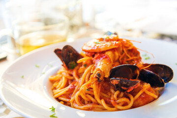 Delicious seafood pasta prepared tomato sauce, mussels and shrimps on top ready to be served in white plate.