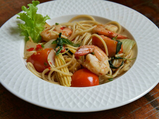 Spicy spaghetti with shrimps close-up on a plate on wooden table. horizontal top view from above.
