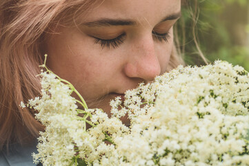 Girl holds in hands elderberry flowers in garden (Sambucus nigra). Elder, black elder flowers....