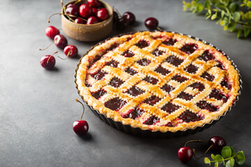 Delicious homemade classic cherry pie with a flaky crust on dark gray background