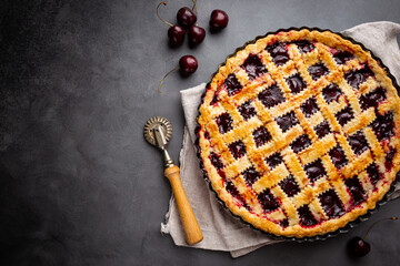 Delicious homemade classic cherry pie with a flaky crust on dark gray background, top view