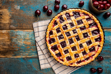 Delicious homemade classic cherry pie with a flaky crust on blue rustic background, top view