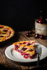 piece of Delicious homemade classic cherry pie with a flaky crust on dark rustic background