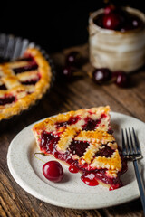 piece of Delicious homemade classic cherry pie with a flaky crust on dark rustic background