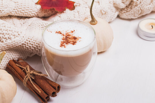 Cup of coffee with milk and cinnamon, autumn leaves and pumpkins