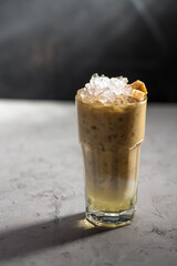 Iced coffee with vanilla syrup and milk on concrete table on black background