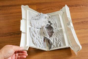 Hand holding the lint trap which have a lot of lint and fiber, wool from cloths after drying in the dryer machine.