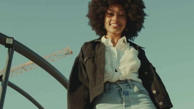 black woman with 70s disco style look dancing funk disco dance outdoors Huge afro hairstyle Black woman have fun and dancing