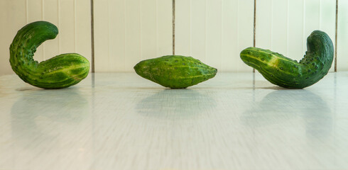 Three deformed cucumbers with yellow stripes lie on the rustic table. Natural vegetables is good...