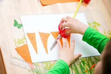 child is doing applique of carrots. each carrot has number and an equivalent number of stems