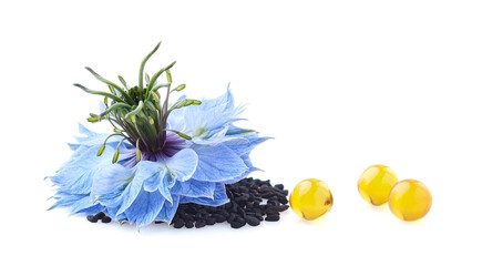Nigella sativa flower and black cumin oil capsules on white background