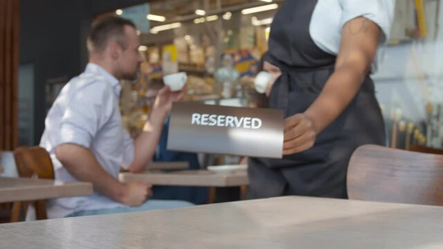 Close up of waiter putting reserved plate on table in restaurant