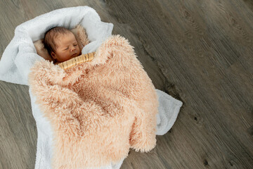 Two week old newborn baby boy sleeping in a vintage wooden box. Shot in the studio on a wood background.