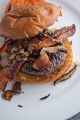 Bacon cheeseburger. Classic American style Burger with two patties, crispy Bacon, melted Swiss cheese, caramelized onions on a toasted brioche and served with crispy French fries. Bar favorite.