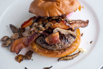 Bacon cheeseburger. Classic American style Burger with two patties, crispy Bacon, melted Swiss cheese, caramelized onions on a toasted brioche and served with crispy French fries. Bar favorite.