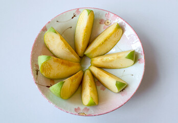 Fototapeta na wymiar A bowl of sliced green apple on white table