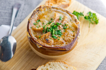 French Onion Soup. Classic traditional french restaurant bistro menu item. French onion soup, yellow onions reduced in broth topped with cheese melted and served with homemade baguettes. 