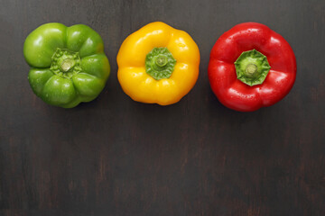 Green, yellow and red pepper isolated on wood. Studio shot.