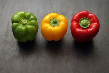 Green, yellow and red pepper isolated on wood. Studio shot.