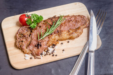 Fresh rare  striploin beef portion steak medium grill with seasoning , herb and spice on wood board and black background.