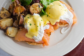 Eggs Benedict. Traditional classical American diner or French Bistro brunch item. Homemade Hollandaise sauce drizzled over a poached egg, country ham on top of a toasted English muffin with avocado.