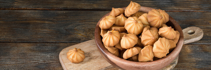 Shortbread in a wooden bowl on a brown wooden table. Top view with space for text. Banner