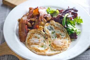 Sunny side up eggs with country potato hash served in a cast iron skillet. muffin with country ham, melted cheese, fried egg & homemade hollandaise sauce. Classic French or American cuisine favorite.