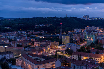 Crossing during late day to night timelapse to Mendel Square in Brno with cars and public transport, trams and buses passing through busy square and the surrounding streets which slowly light