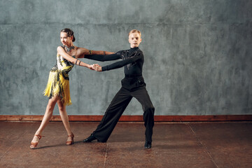 Young couple sport dancers dancing in ballroom dance cha-cha-cha.