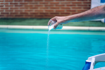 Person cleaning and chlorinating the pool on a hot summer afternoon, is running the cleaner and...