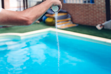 Person cleaning and chlorinating the pool on a hot summer afternoon, is running the cleaner and...