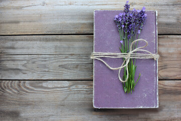 Old book decorated with lavender flowers and tied with jute twine on wooden table. Copy space. Selective focus

