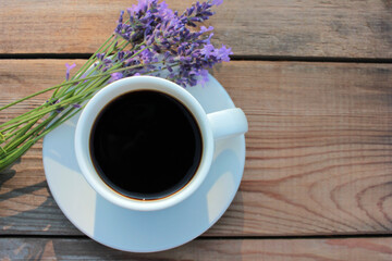 Cup of coffee with lavender flowers on wooden table background with copy space. Summer morning coffee. Top view