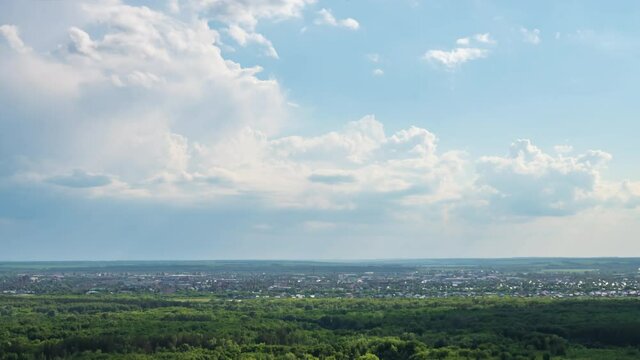 Timelapse. White Cumulus clouds high in blue sky over the city and green hills