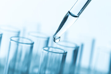 pipette with a drop and scientific laboratory test tubes in a research laboratory.