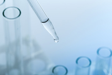 pipette with a drop and scientific laboratory test tubes in a research laboratory.