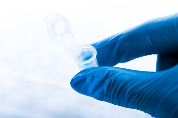 Fototapeta premium gloved hand and laboratory test tubes in a laboratory. virus or vaccine testing
