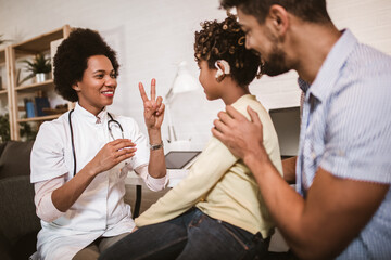 Smiling deaf african american girl with ear implant at doctor's office.