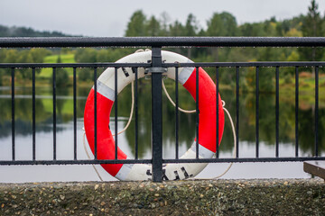 Fototapeta na wymiar Lifebuoy on the fence next to the water. The inscription in Norwegian: Safe.