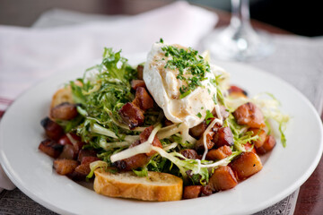 Salad. Frisee lettuce dress with olive oil and balsamic vinegar and topped with bacon lardons a fried egg and garnished with italian parsely and a toasted baguette. Served in a French Bistro.