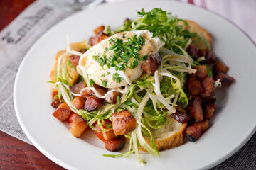 Salad. Frisee lettuce dress with olive oil and balsamic vinegar and topped with bacon lardons a fried egg and garnished with italian parsely and a toasted baguette. Served in a French Bistro.