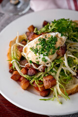 Salad. Frisee lettuce dress with olive oil and balsamic vinegar and topped with bacon lardons a fried egg and garnished with italian parsely and a toasted baguette. Served in a French Bistro.