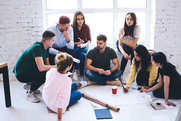 Working process of group of casually dressed male and female colleagues making preparation for designing new office, creative architects drafting during informal meeting discussing ideas together