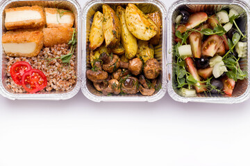 Home delivery concept. On a white plate porridge with vegetables and cheese, salad and potatoes with mushrooms. Copy space