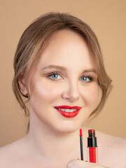 Girl holds red lipstick and smiles 