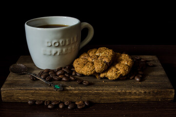 Cup of coffee on wooden tray with black background and cookies and coffee beans