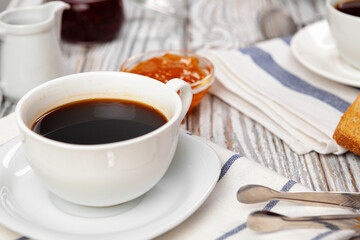 White cup of coffee on wooden kitchen table