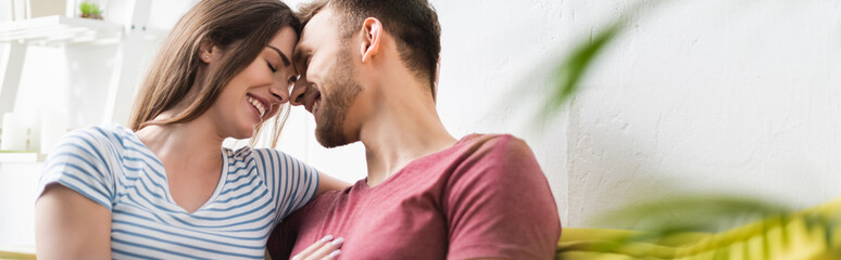 Naklejka premium smiling beautiful young couple hugging at home, panoramic orientation